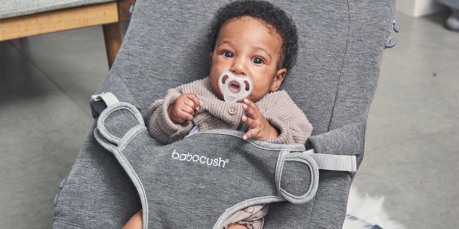 Infant with pacifier sitting in Babocush baby bouncer