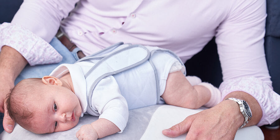 Baby resting on Babocush comfort cushion with father